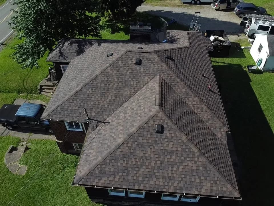Aerial view of a completed architectural shingle roof with hip and gable sections